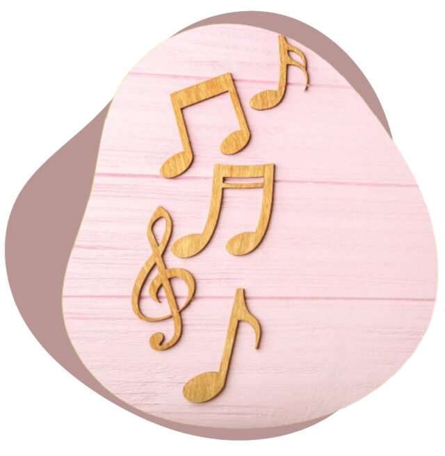 Gold treble clef and music note shapes on a pink wooden background